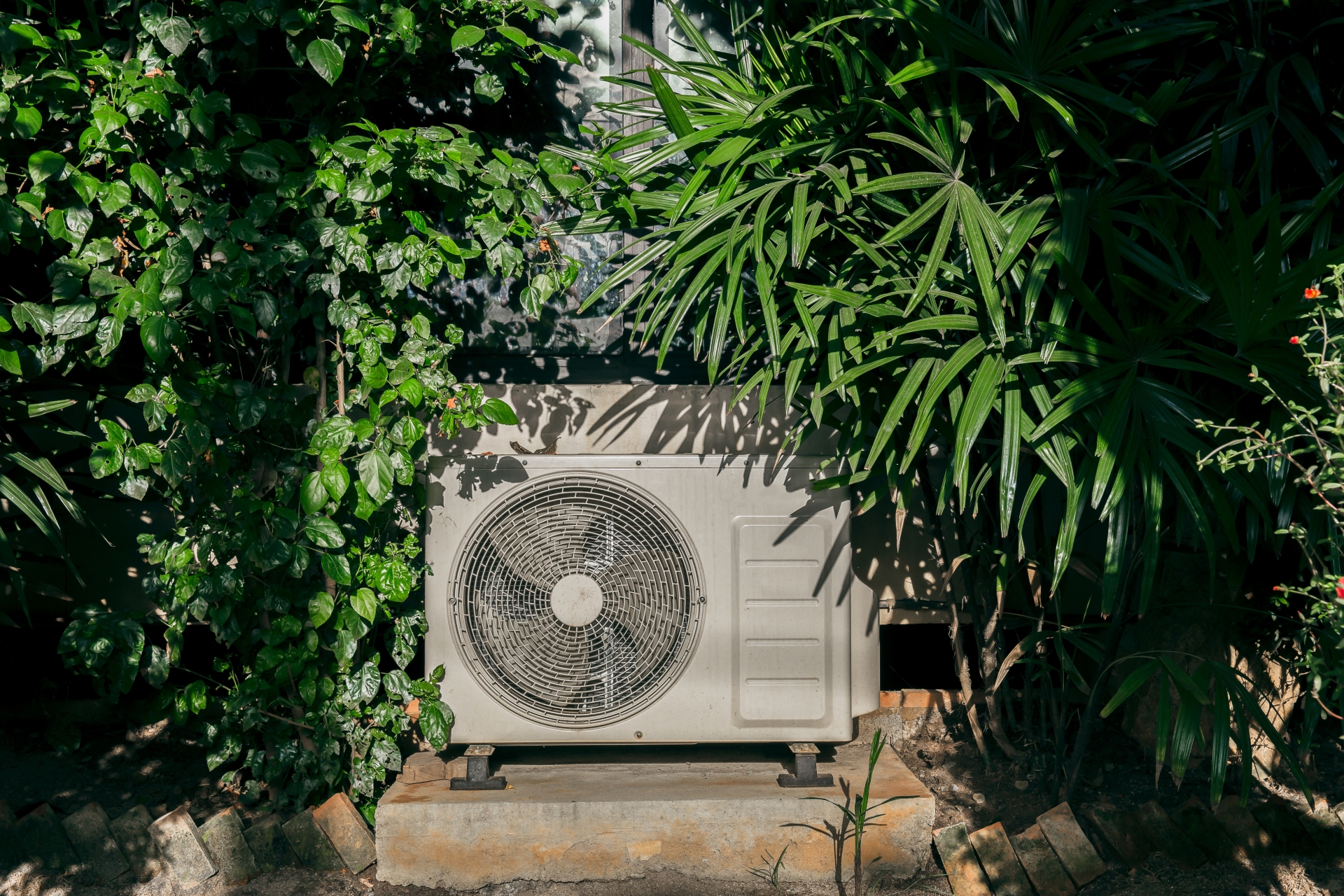 heat pump surrounded by greenery and plants outside