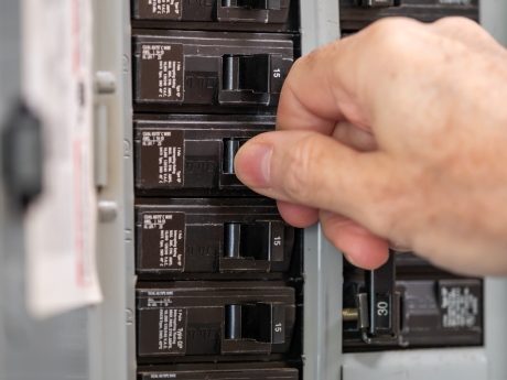person turning on electrical panel