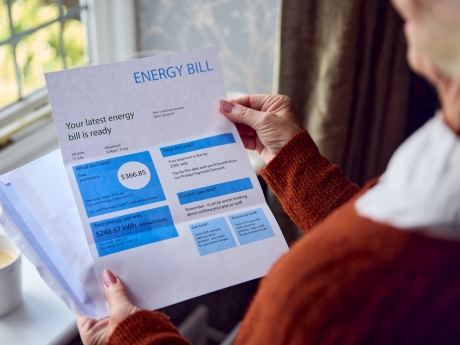 Woman holding energy bill and reviewing charges